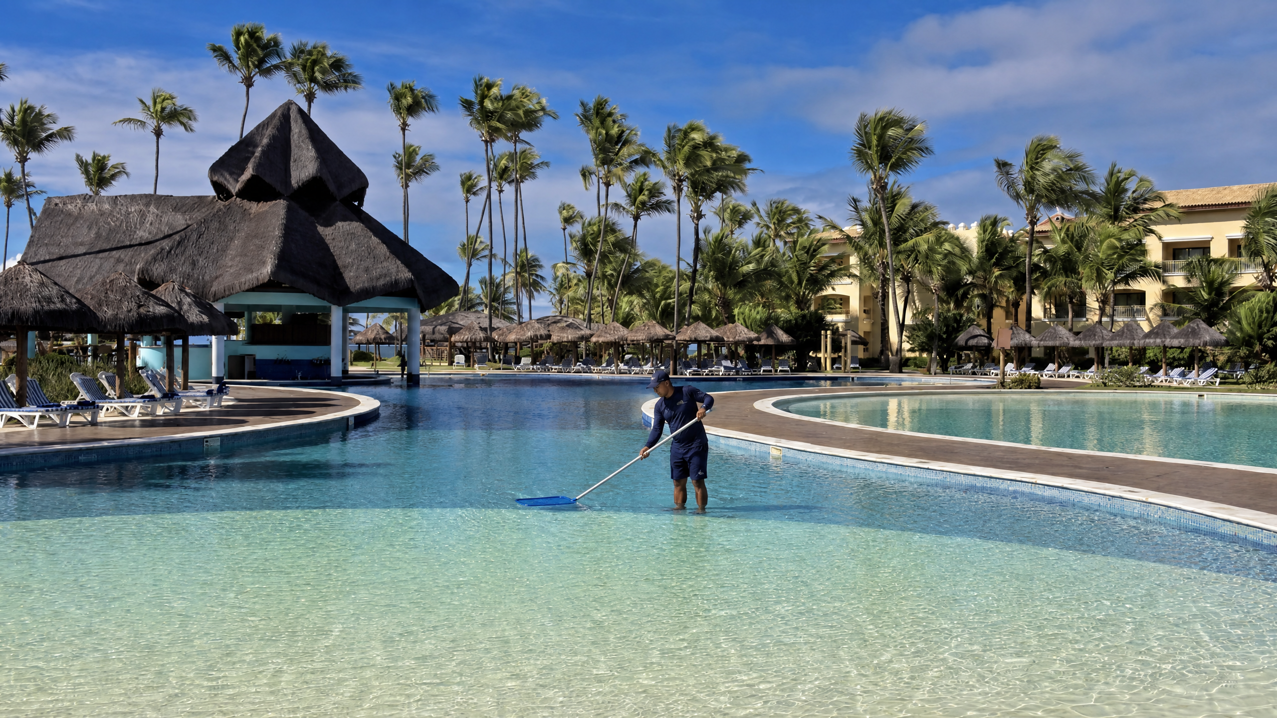 Piscineiro realizando manutenção em piscina de resort